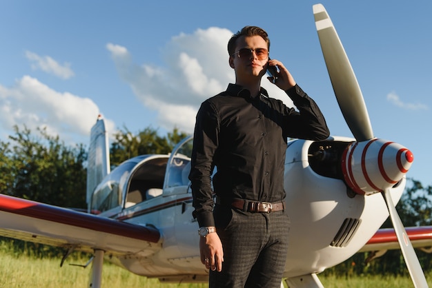 Joven empresario guapo de pie cerca de avión privado