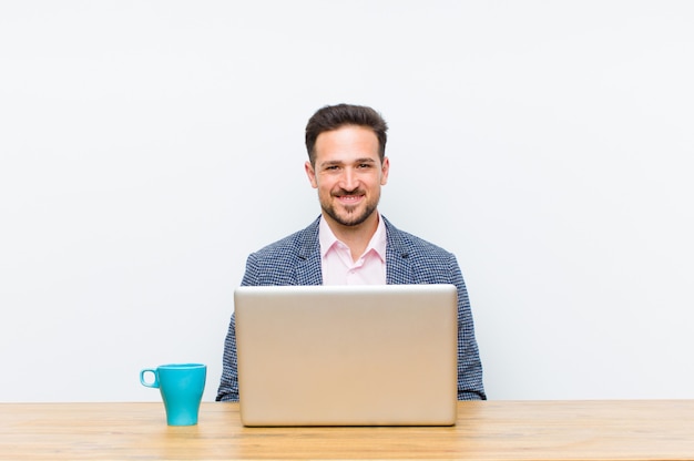 Joven empresario guapo sonriendo positivamente y con confianza, mirando satisfecho, amable y feliz