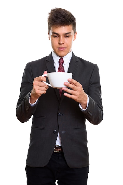 joven empresario guapo sosteniendo y mirando la taza de café