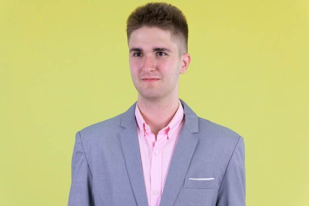 Joven empresario guapo en traje contra la pared de color