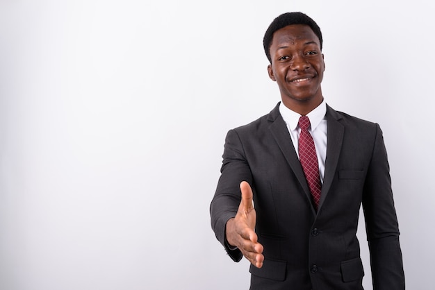 Joven empresario guapo vistiendo traje contra un blanco