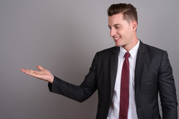 joven empresario guapo vistiendo traje en gris