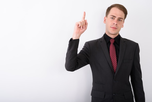 Joven empresario guapo vistiendo traje en pared blanca