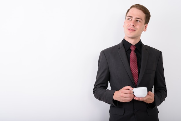 Joven empresario guapo vistiendo traje en pared blanca