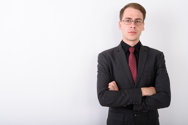 Joven empresario guapo vistiendo traje en pared blanca