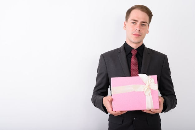 Joven empresario guapo vistiendo traje en pared blanca