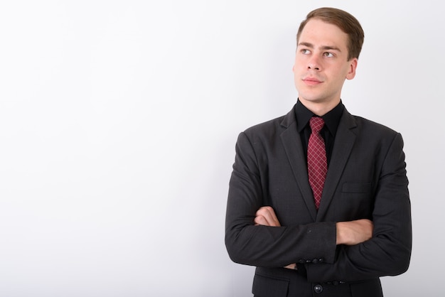 Joven empresario guapo vistiendo traje en pared blanca