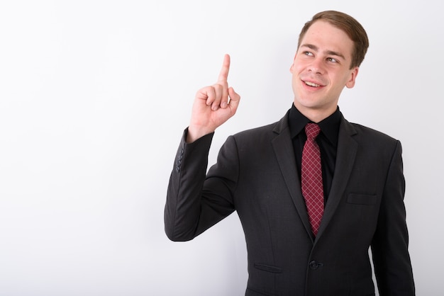 Joven empresario guapo vistiendo traje en pared blanca