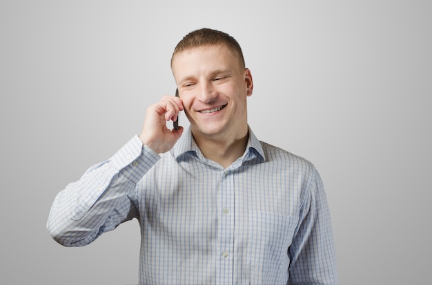 Joven empresario hablando por un teléfono celular. Aislado en la superficie blanca