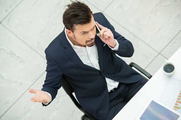 Foto joven empresario está hablando por teléfono en el trabajo.