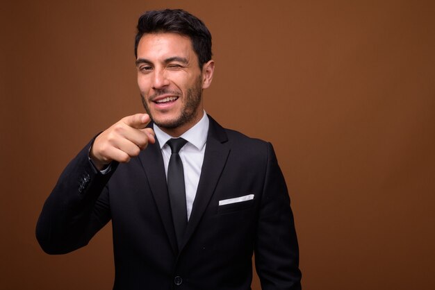 Joven empresario hispano guapo contra el fondo marrón