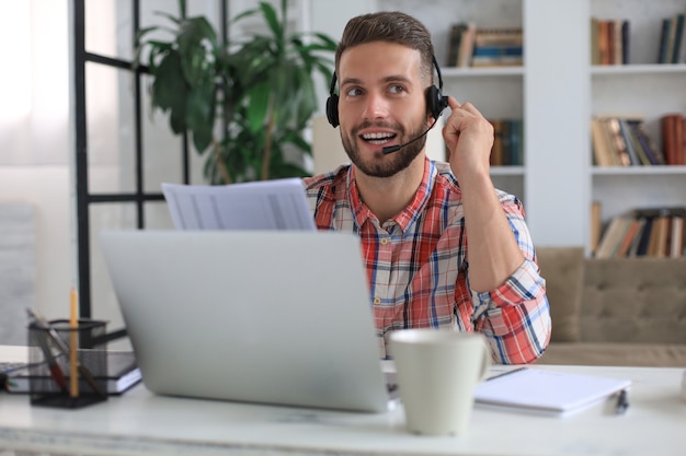 Joven empresario independiente concentrado que usa la computadora portátil para videoconferencia, trabajando de forma remota en línea en casa.