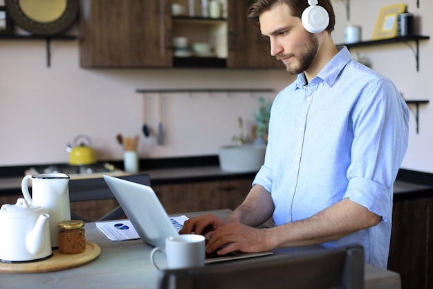 Joven empresario independiente concentrado que usa la computadora portátil para videoconferencia, trabajando de forma remota en línea en casa.