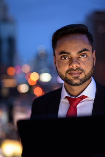 Joven empresario indio barbudo contra la vista de la ciudad por la noche