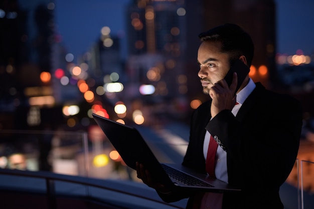 Joven empresario indio barbudo contra la vista de la ciudad por la noche