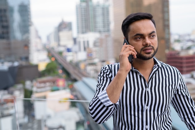 Joven empresario indio barbudo contra la vista de la ciudad