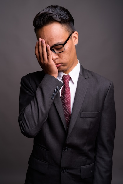 Joven empresario indio guapo contra la pared gris