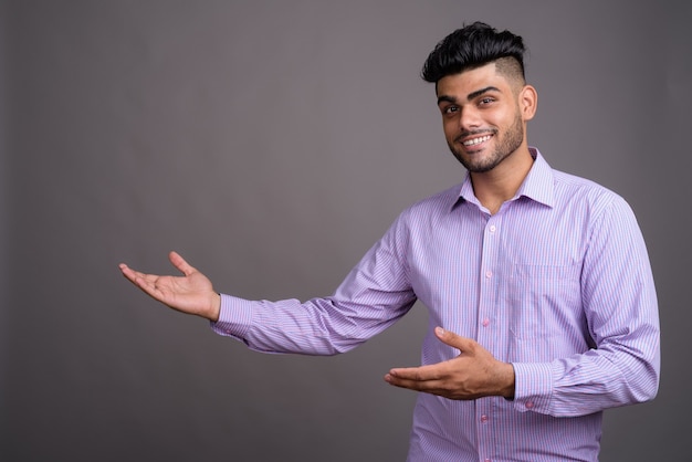 Joven empresario indio guapo contra la pared gris