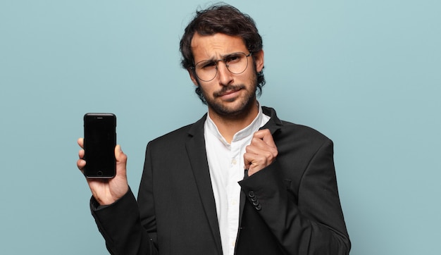 Joven empresario indio guapo mostrando su pantalla vacía de teléfono