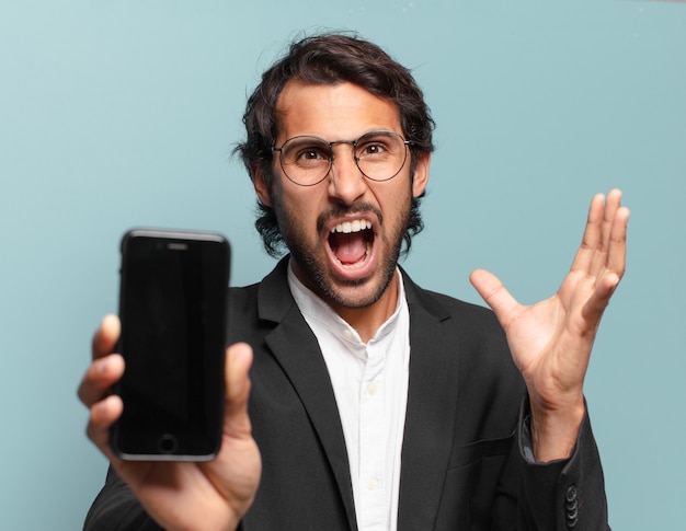 Joven empresario indio guapo mostrando su pantalla vacía de teléfono