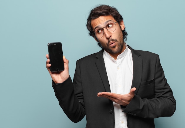 Joven empresario indio guapo mostrando su pantalla vacía de teléfono