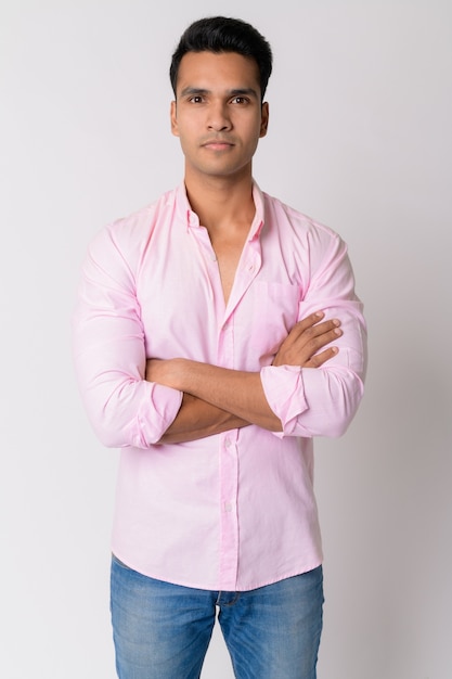 Joven empresario indio guapo vistiendo camiseta rosa contra la pared blanca