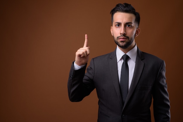 Joven empresario iraní barbudo guapo contra la pared marrón