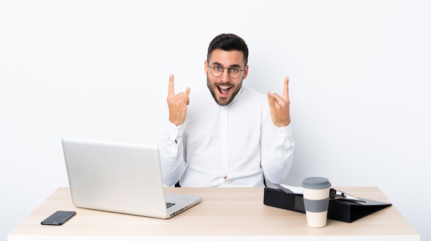 Joven empresario en un lugar de trabajo haciendo gesto de rock