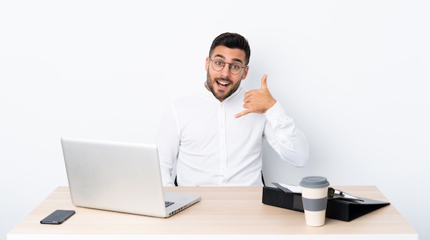 Joven empresario en un lugar de trabajo haciendo gesto de teléfono. Llámame señal de vuelta