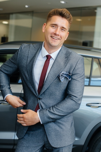 Un joven empresario mira un coche nuevo en un concesionario de coches. Comprando un carro.