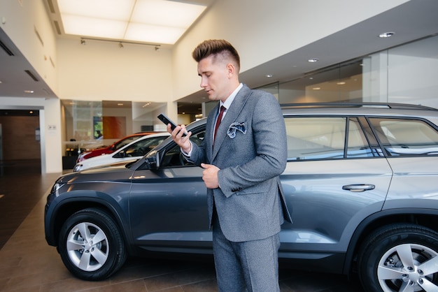 Un joven empresario mira un coche nuevo en un concesionario de coches