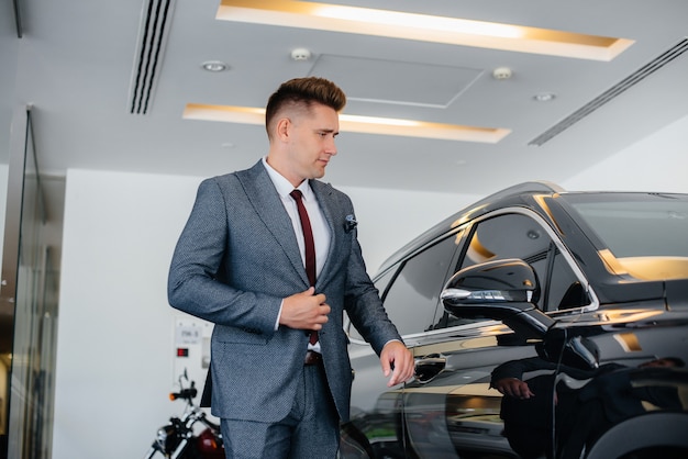 Joven empresario mira un coche nuevo en un concesionario de coches