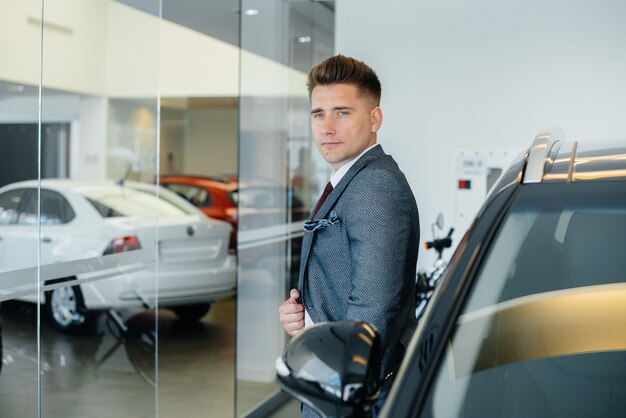 Un joven empresario mira un coche nuevo en un concesionario de coches