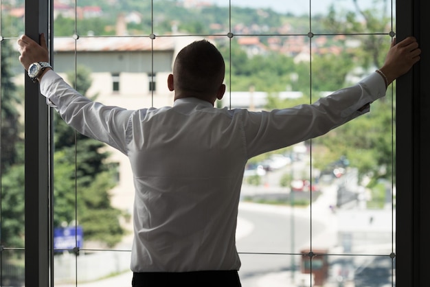 Joven Empresario Mirando Por La Ventana De La Oficina Reflexionando Sobre El Futuro