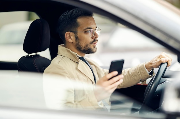 Foto un joven empresario de moda conduce su automóvil y usa un teléfono