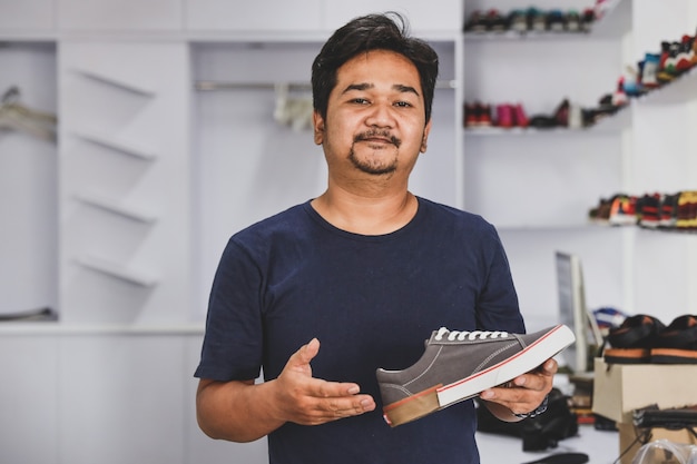 Foto joven empresario mostrando u ofreciendo un zapato en su tienda de moda