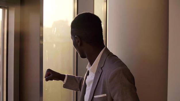 Joven empresario negro mirando por la ventana en la oficina