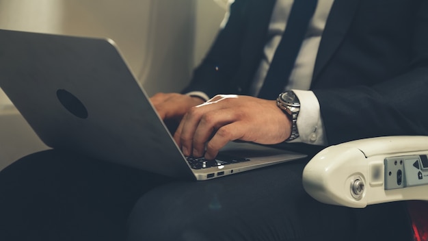 Joven empresario con ordenador portátil en avión. Concepto de viaje de viaje de negocios.