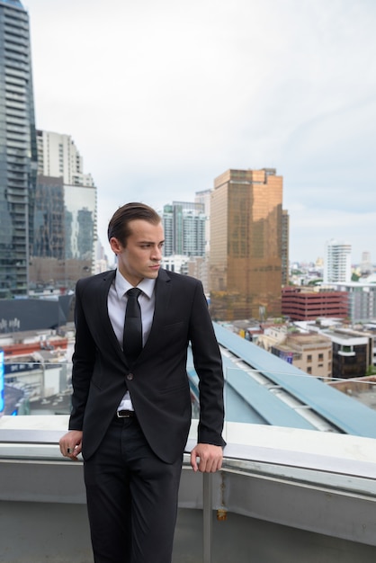 Joven empresario pensando al aire libre en la ciudad con vistas a la azotea