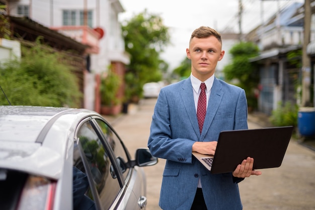 Joven empresario con portátil en las calles al aire libre