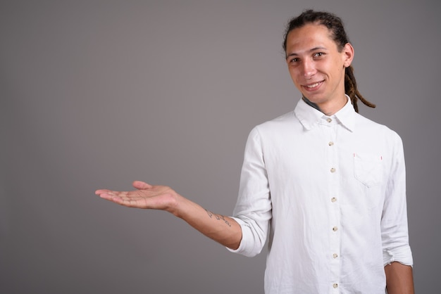 Joven empresario con rastas contra un fondo gris