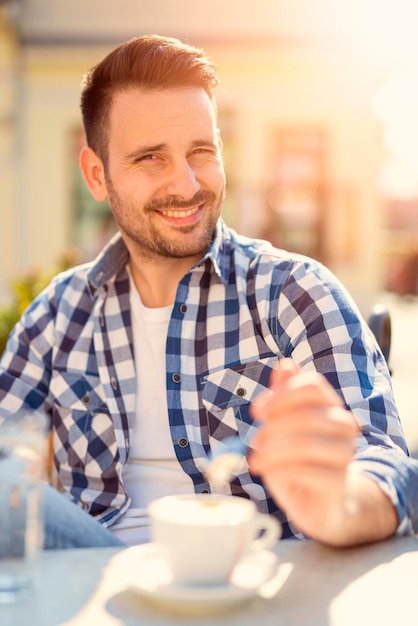 Joven empresario sentado en un café en un descanso para tomar café