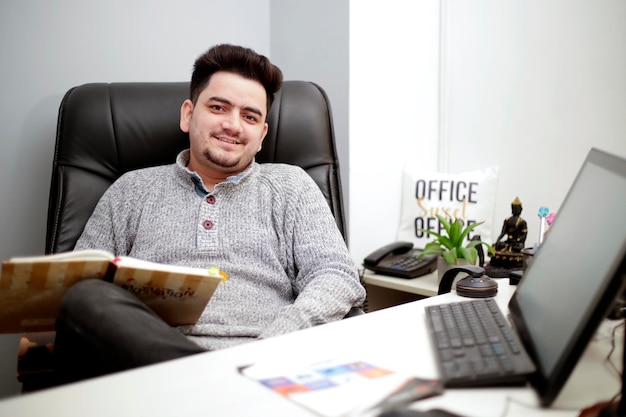 Foto un joven empresario está sentado en el cargo y sonriendo.