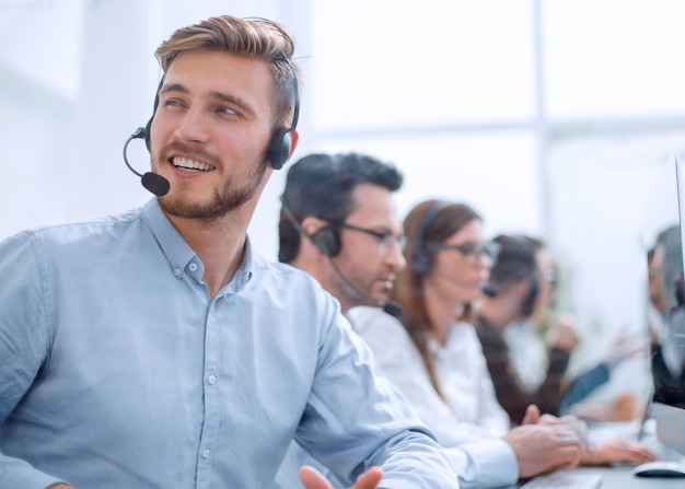 Joven empresario sentado a la mesa en el call centerpersonas y tecnología