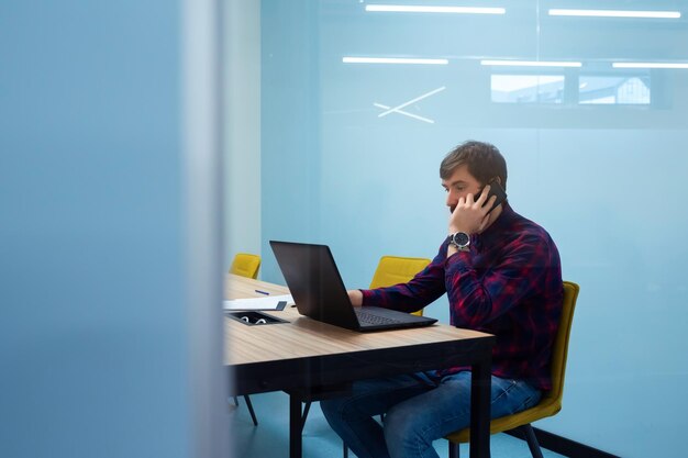 Joven empresario sentado en la mesa de la oficina trabajando en la oficina