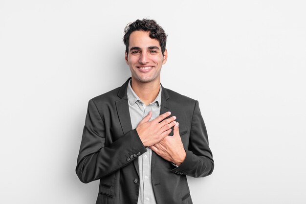 Joven empresario sintiéndose romántico, feliz y enamorado, sonriendo alegremente y tomados de la mano cerca del corazón