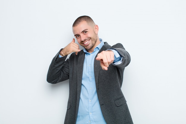 Joven empresario sonriendo alegremente y señalando mientras hace una llamada más tarde gesto