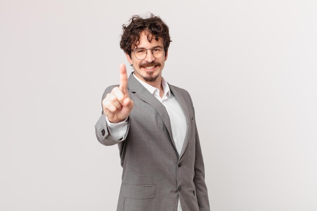 joven empresario sonriendo con orgullo y confianza haciendo el número uno