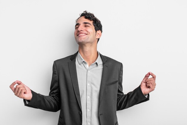 Joven empresario sonriendo sintiéndose despreocupado, relajado y feliz bailando y escuchando música divirtiéndose en una fiesta