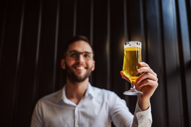 Foto joven empresario sonriente en camisa con vaso de cerveza.